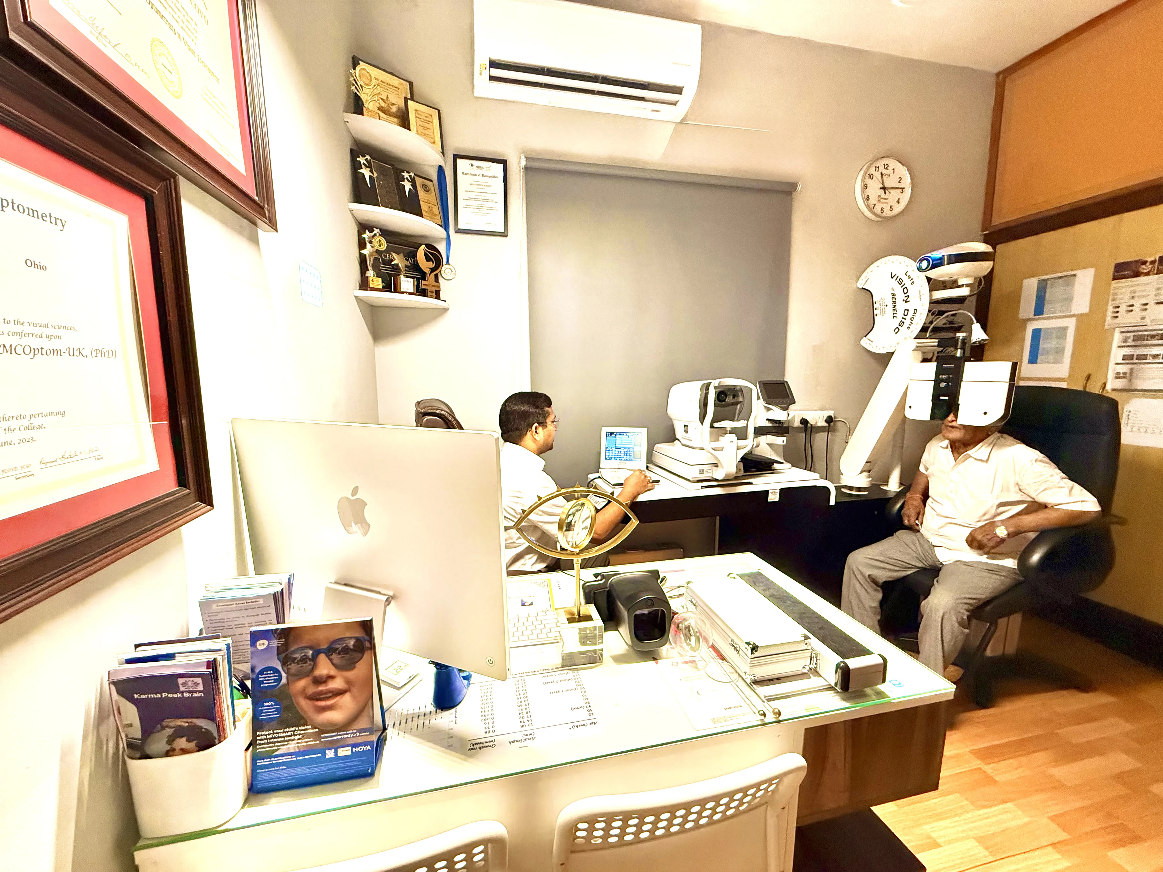 Caring Vision Therapy Ashok Nagar Chennai – Doctor in consultation room with patient, auto-refractor and professional credentials on wall