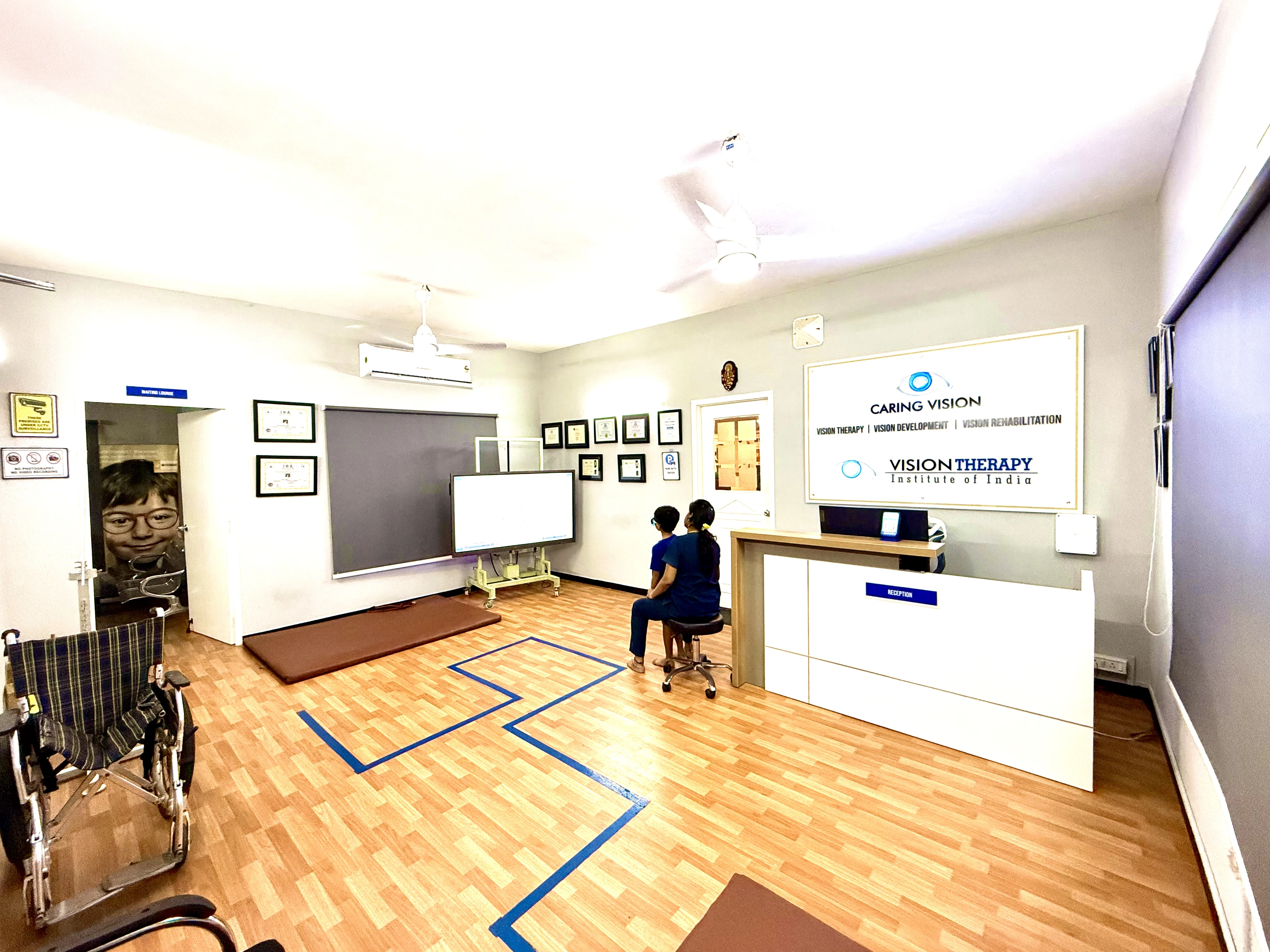 Caring Vision Therapy Ashok Nagar Chennai – Main clinic floor showing reception counter, interactive display screen and wheelchair-accessible space