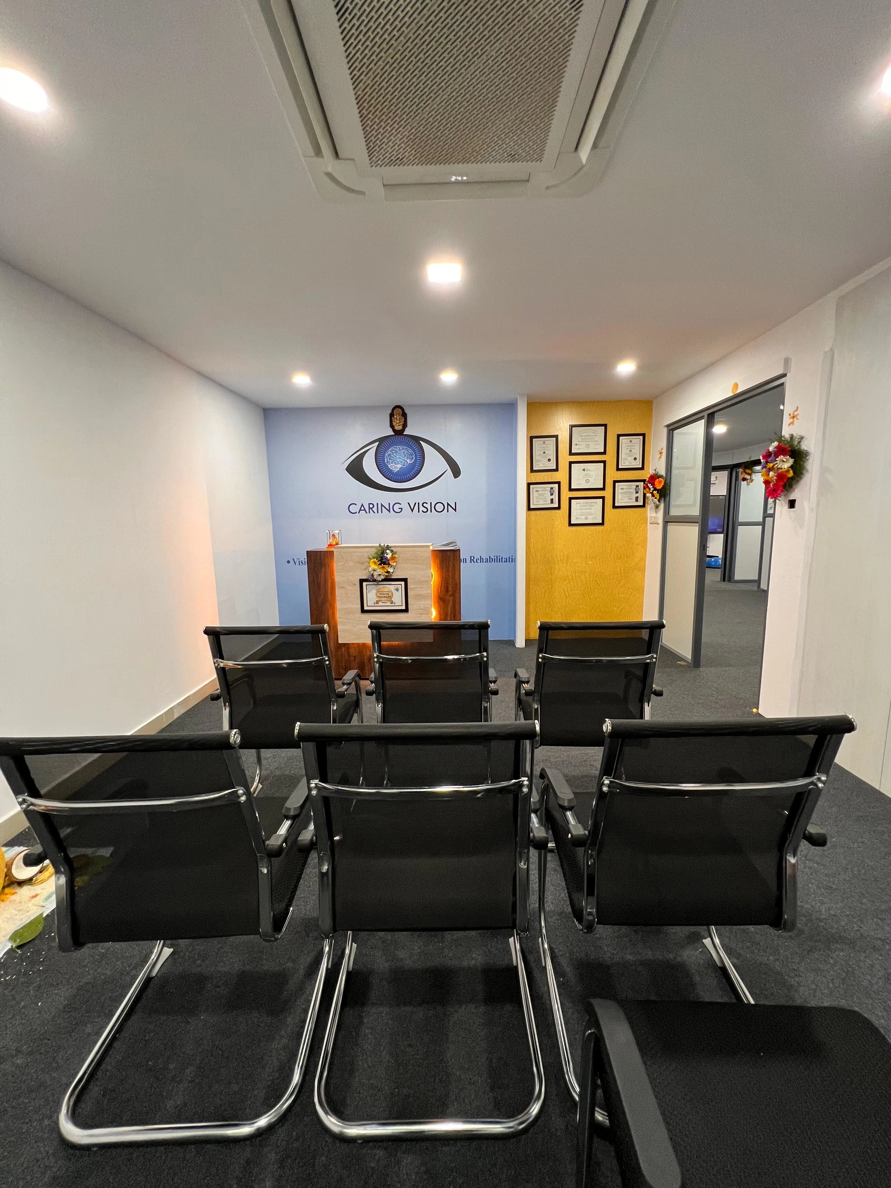 Caring Vision Therapy Hyderabad – Patient waiting area and reception with rows of chairs and branded feature wall
